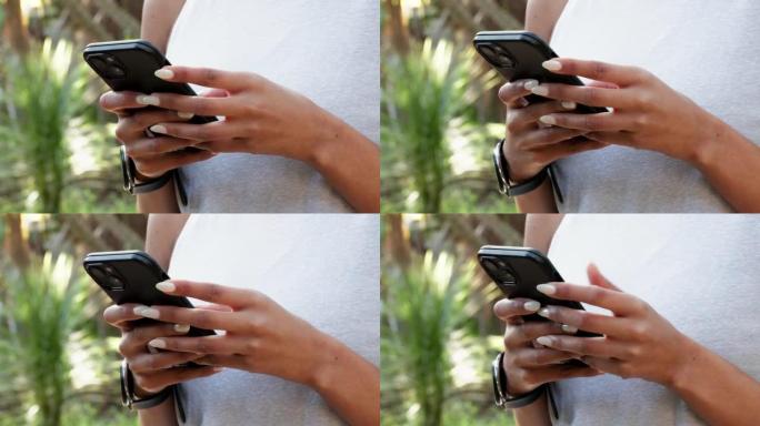 一个女人站在户外时在电话上向她的朋友输入短信的特写镜头。女孩联网或在互联网上进行研究，移动应用程序或