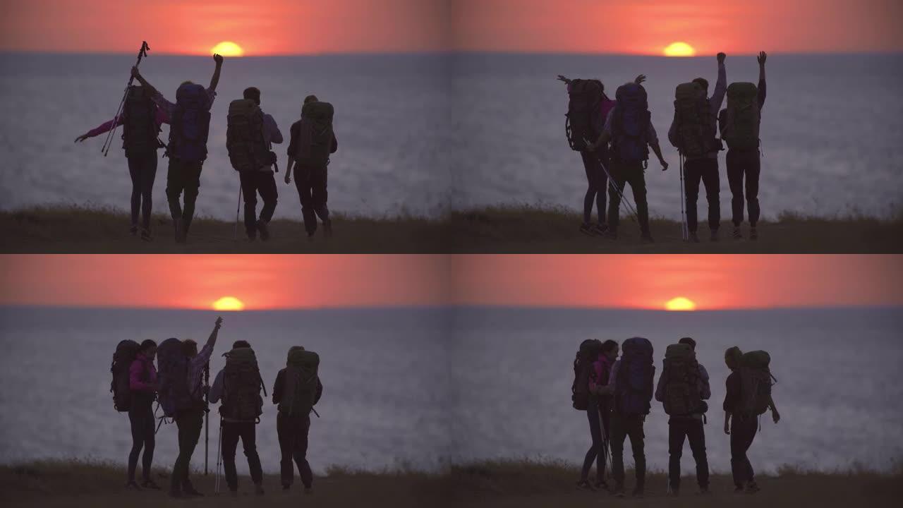 日落背景下步行到海边的四个旅行者