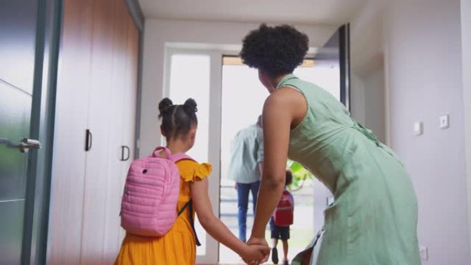 父母帮助女儿从前门离开家并一起上学时穿上背包-慢动作拍摄