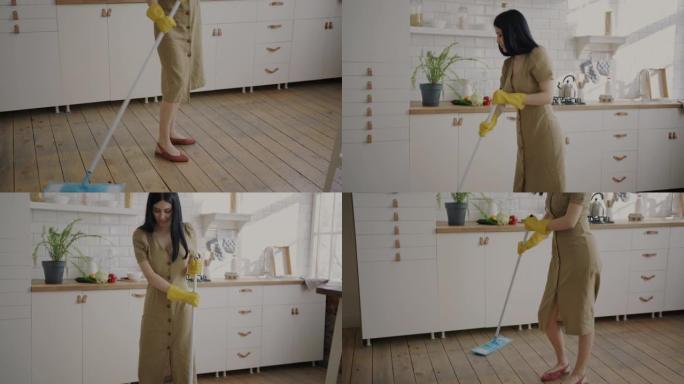 快乐的年轻女士在厨房洗地板，在闲暇时跳舞，玩得开心