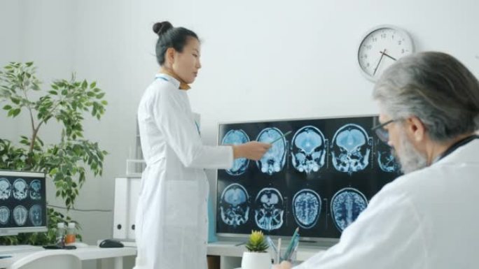 医生同事讨论MRI脑部扫描指向医院办公室的数字屏幕