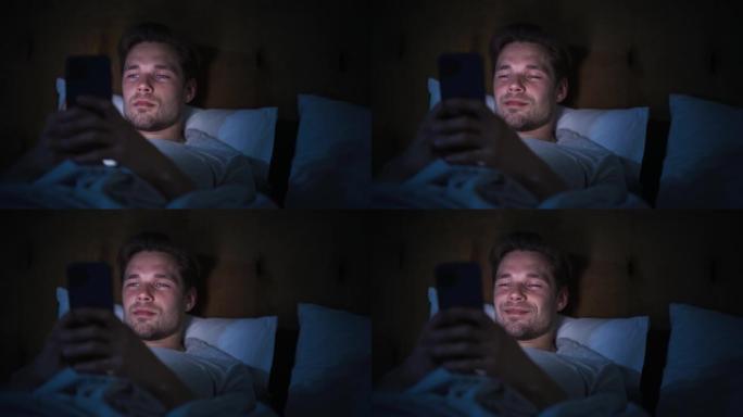 匿名男子晚上在家床上使用智能手机。帅哥浏览社交媒体，看新闻，深夜网购。专注手握手机遮脸