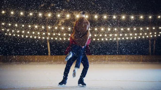 浪漫的冬天下雪的夜晚: 滑冰夫妇在溜冰场上玩得开心。双人滑冰boyfried抬起他美丽的女友并旋转。