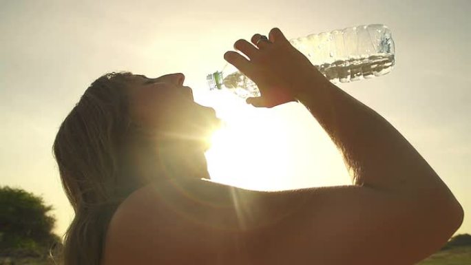 慢动作: 年轻女子在日落时喝水