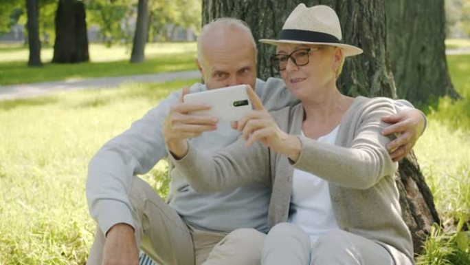 在公园里享受夏日的智能手机相机自拍的高级男人和女人