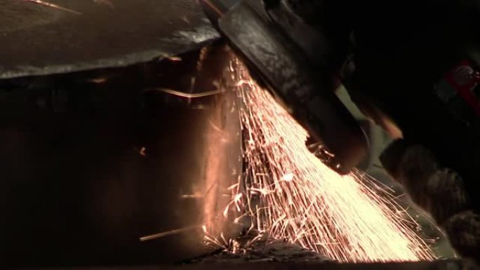 一个人使用角磨机在金属上打磨，产生大量火花。特写。