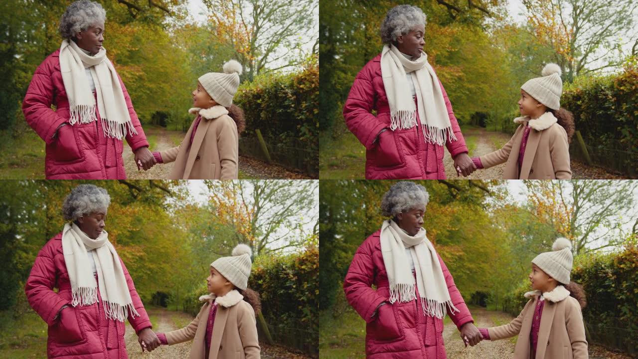 祖母与孙女牵着手一起穿越秋天的乡村