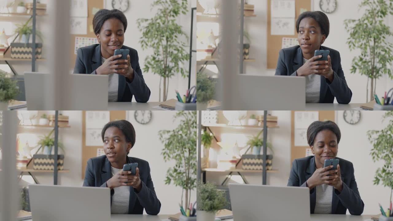 开朗的上班族在工作场所使用智能手机触摸屏并微笑着看着显示器