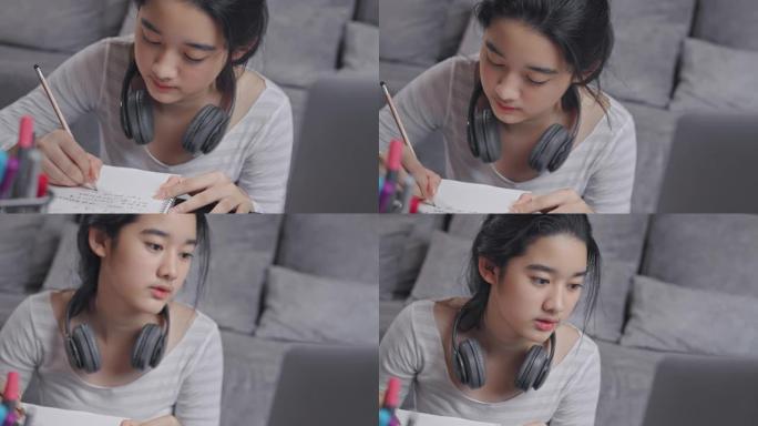 特写镜头4k分辨率迷人的亚洲少女戴着耳机，在冠状病毒或covid 19锁定时，与老师一起在笔记本电脑