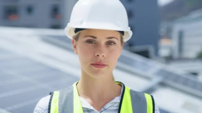 一名年轻的白人妇女在安装太阳能电池板时戴着安全帽。一位自信的女员工站在建筑工地的建筑物上的肖像