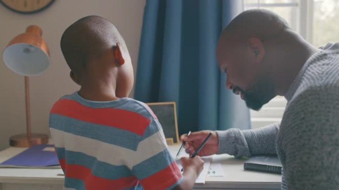 4k视频片段，一个英俊的成熟男人在卧室里帮助儿子做作业