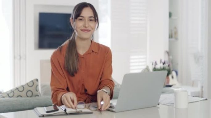 年轻女商人在家庭办公室使用笔记本电脑和阅读笔记本电脑的肖像。微笑的企业家致力于创业和计划成功。拥有家