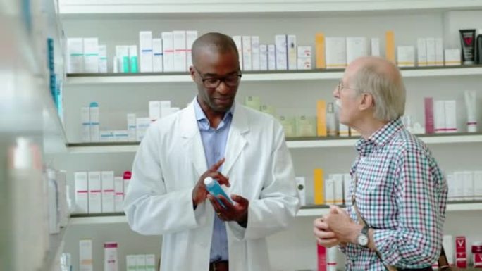 非洲男性药剂师在药店向男人展示药物时交谈