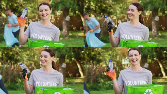 微笑的白人妇女穿着志愿者t恤，拿着回收板条箱，收集塑料垃圾