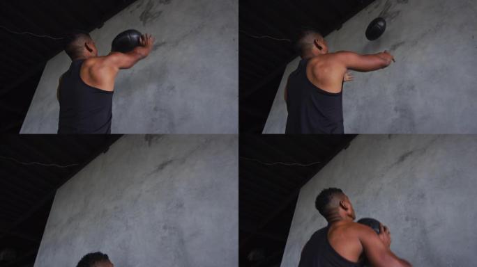 非裔美国男子在空荡荡的城市建筑里用药球锻炼