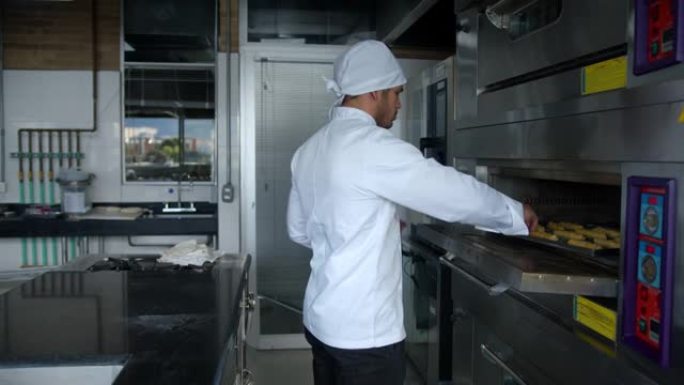 拉丁美洲男性面包师将一盘糕点放入烤箱