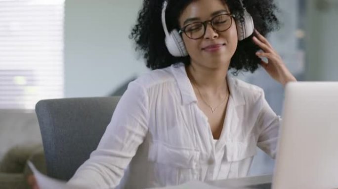 4k视频片段，一个有吸引力的年轻女学生在笔记本电脑上在家学习时听音乐