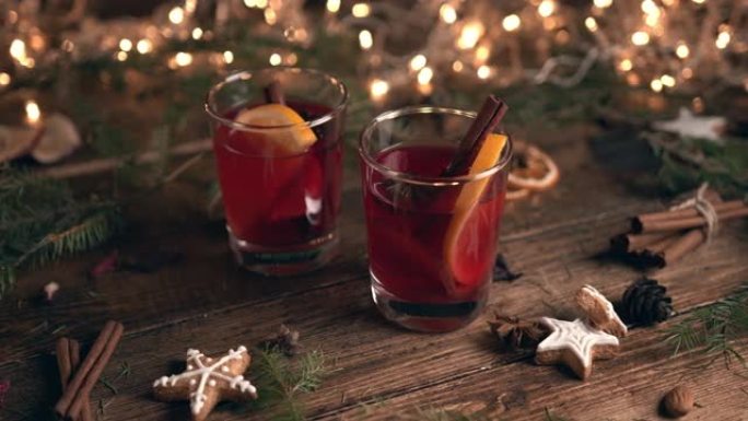 盛满橘子和肉桂的热葡萄酒的玻璃杯，周围是冷杉树枝和香料