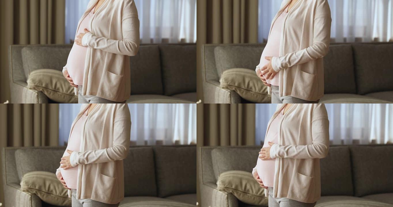 孕妇独自站在客厅抚摸腹部