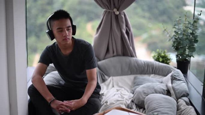 一个亚洲华裔少年男孩用耳机听音乐