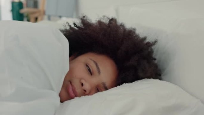 睡个好觉后躺在床上，开心，微笑并以积极的心态醒来。早上无忧无虑，满足和休息的黑人妇女。在卧室睡觉时放