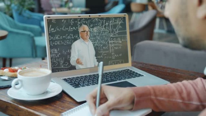 阿拉伯人在咖啡馆用现代笔记本电脑观看在线网上研讨会学习和写作
