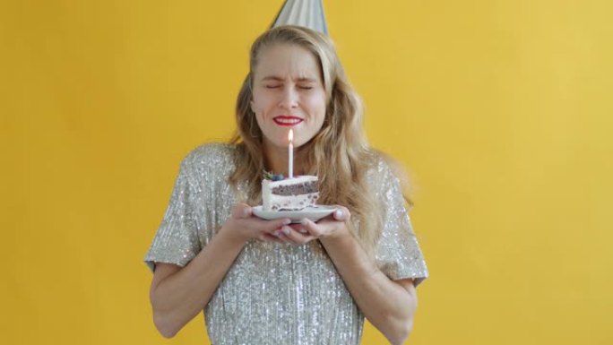 年轻女子在生日蛋糕上吹蜡烛许愿的慢动作肖像