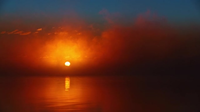 充满活力的橙色日出穿过宁静湖上的云层