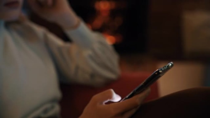 SLO MO DS年轻女子在一个背景为壁炉的房间里使用她的智能手机