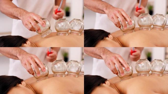 水疗，玻璃和拔罐疗法用于背部疼痛，通过物理疗法治疗和放松身体和背部肌肉。治疗师和女性患者在床上进行深