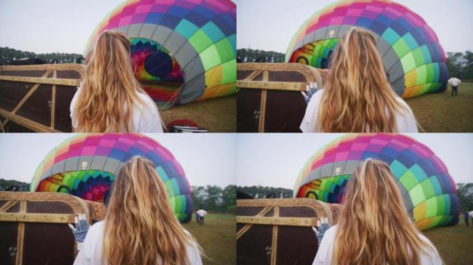 年轻女飞行员的真实慢动作正在飞行前控制着五颜六色的热气球正在充气。