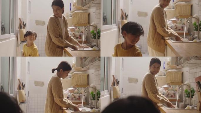 亚洲迷人的母亲教小男孩打扫厨房。