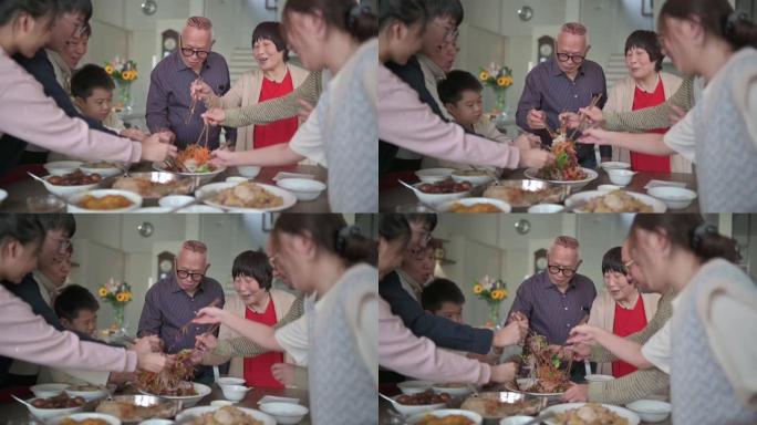 亚洲华人mutli世代家庭在团圆饭中与传统美食Lou sang (生鱼菜) 庆祝除夕