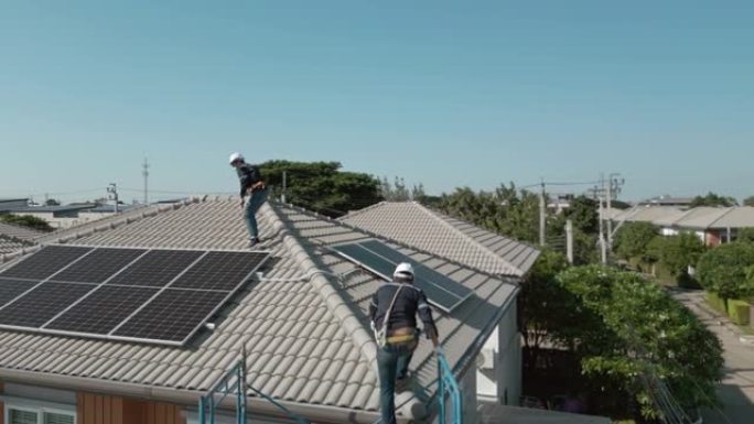 房屋屋顶上的两名工程师的鸟瞰图组装光伏面板。