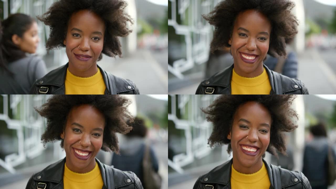 一个快乐而时髦的女人独自在城市里通勤时笑的肖像。一个美丽的黑人女性的脸，一个黑人微笑着，看起来很自信