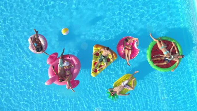 空中: 游客在五颜六色的漂浮物上放松，同时在游泳池享受阳光明媚的一天。