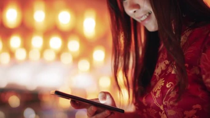 在中国城镇地区的农历新年灯笼上使用电话的妇女