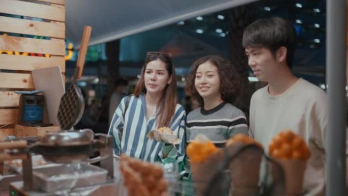 年轻的亚洲朋友在夜市享受街头美食。