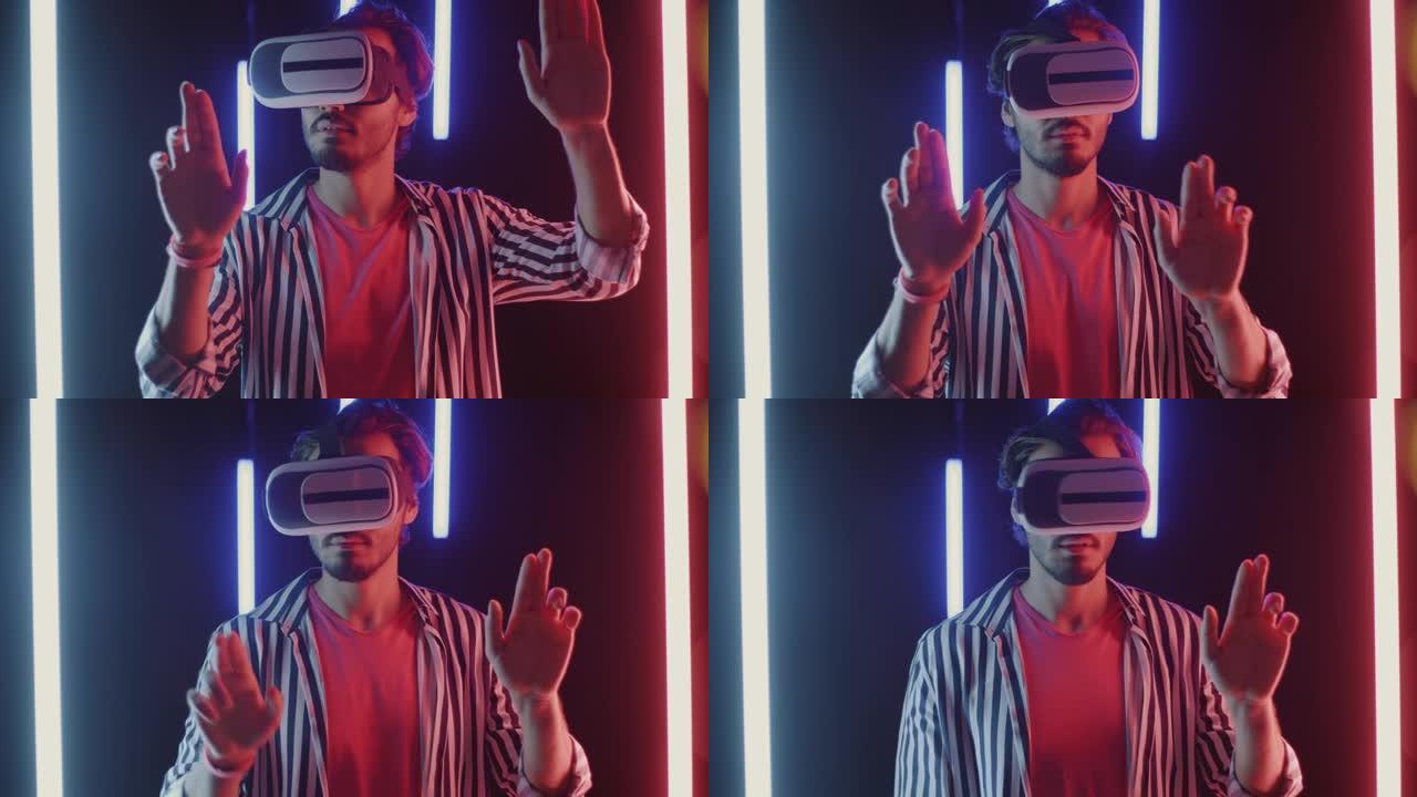 戴着虚拟现实眼镜的年轻人在霓虹灯照明的黑暗背景上玩游戏移动手