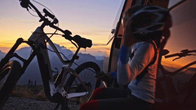 日出时，女人在山顶的货车上给电动自行车充电