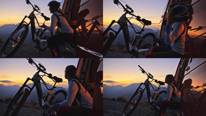日出时，女人在山顶的货车上给电动自行车充电