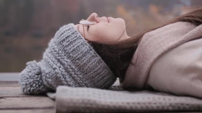 年轻女子躺在湖码头的毯子上
