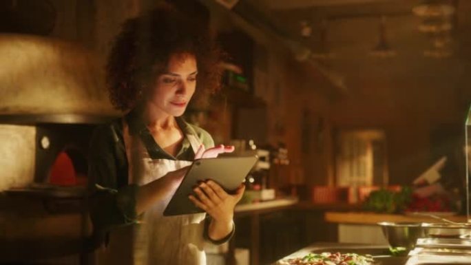 餐厅: 美丽的女厨师使用数字平板电脑。正宗的比萨店烹饪美味的有机生态食品。在她的小型企业家庭商店工作