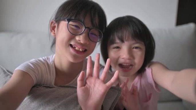 亚洲华裔年轻女孩在沙发上的客厅在线使用数字平板电脑与父亲交谈