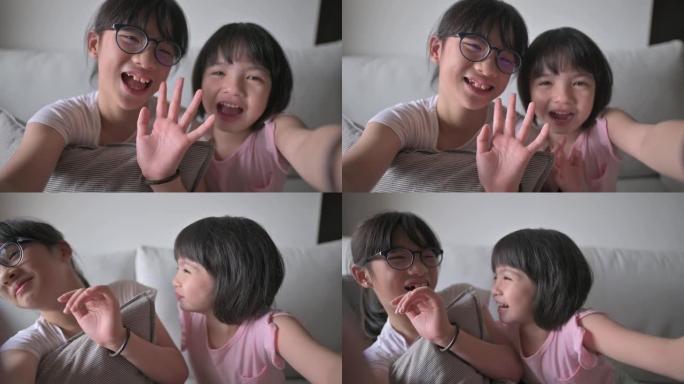 亚洲华裔年轻女孩在沙发上的客厅在线使用数字平板电脑与父亲交谈