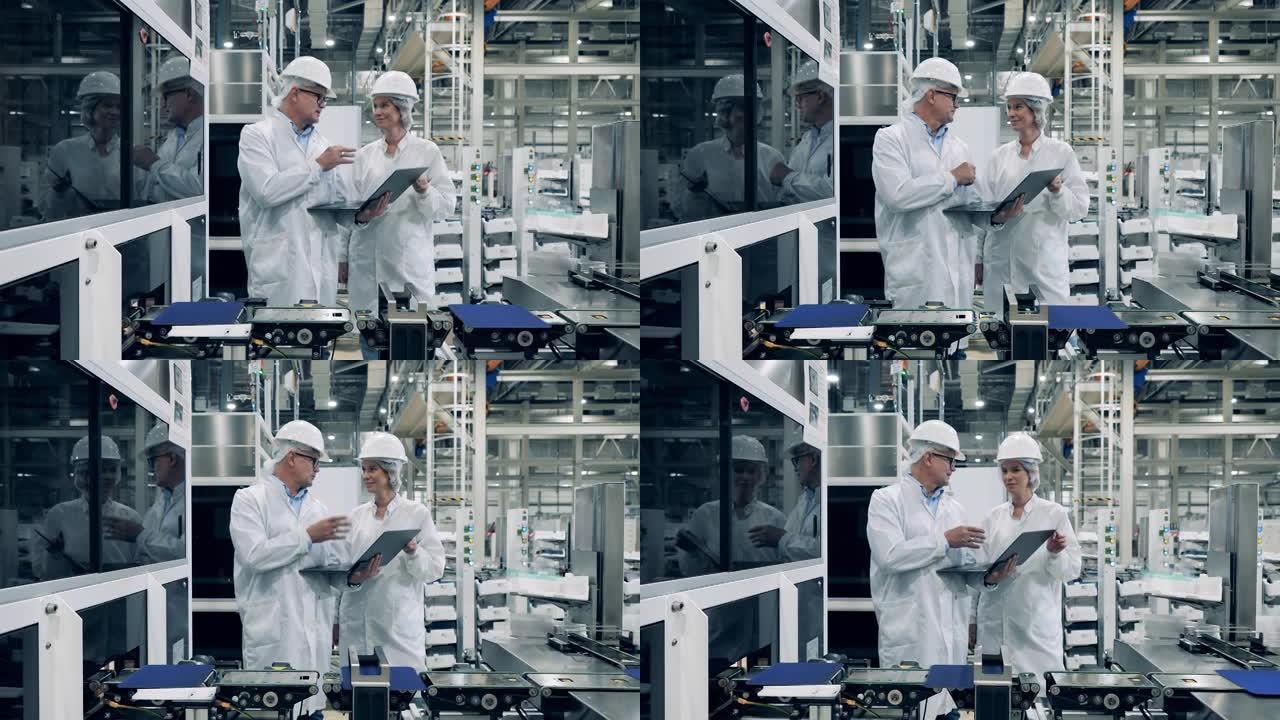 工厂设施的现代工程师。两名专家正在太阳能电池输送机旁边交谈