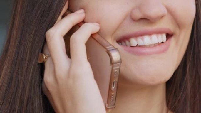 快乐的女人在电话里说话、聊天、说话，同时微笑着，心情愉快。具有完美洁白牙齿和健康口腔卫生习惯的女性的