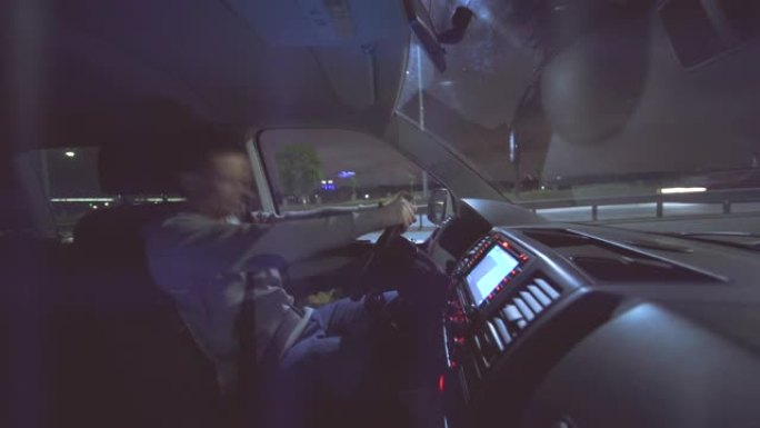 这位拥有智能手机的好斗男子坐在夜城路上的车里