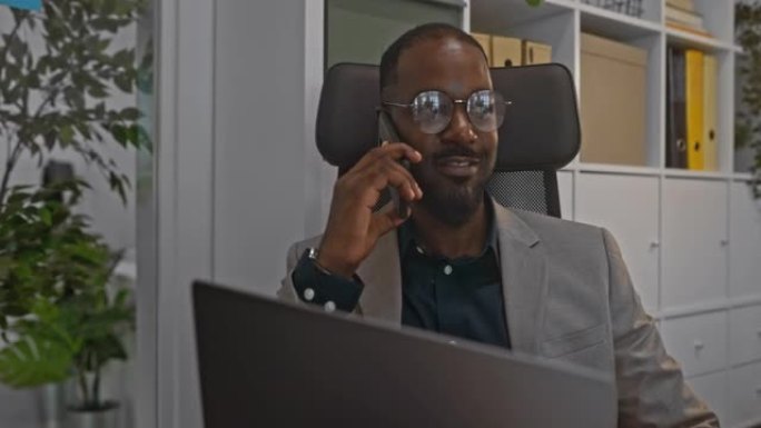 商人在办公室的笔记本电脑上使用智能手机聊天