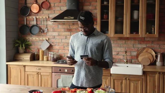 站在厨房里的非洲男子在网上订购食物